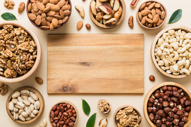 mixed nuts in wooden bowl. Mix of various nuts on colored background. pistachios, cashews, walnuts, hazelnuts, peanuts and brazil nuts. - Photo, image