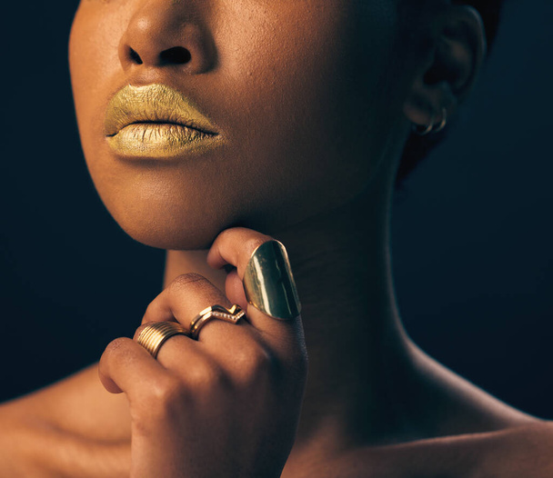 Closeup, jewelry and black woman with foundation, makeup and grooming against dark studio background. Zoom, female and lady with gold lipstick, rings and cosmetics for skincare, aesthetic and luxury. - Valokuva, kuva