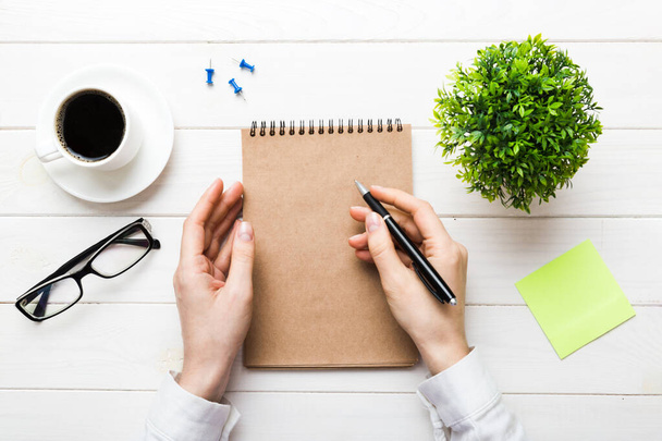 Frauenhand mit Bleistift auf Notizbuch und Kaffeetasse. Frau arbeitet an Bürotisch mit Kaffee. - Foto, Bild