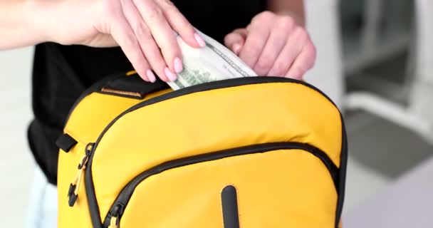Zbliżenie, młode kobiety wkładają dolary do żółtego plecaka. Przygotowanie do podróży, przygoda - Materiał filmowy, wideo