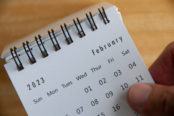 Vista dall'alto di mano flipping febbraio 2023 calendario. Concetto calendario. - Foto, immagini