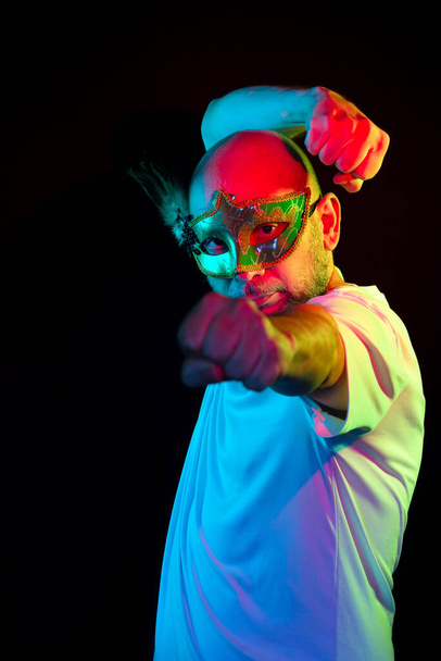 Man portrait, bald, wearing carnival mask, looking at the camera. Isolated in the black background. - 写真・画像