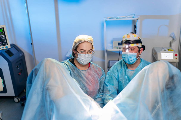 Ammattitaitoinen kirurgit proctologist suorittaa operaation käyttämällä erityisiä lääkinnällisiä laitteita leikkaussalissa sairaalassa. Kiireellinen kirurginen käsite - Valokuva, kuva