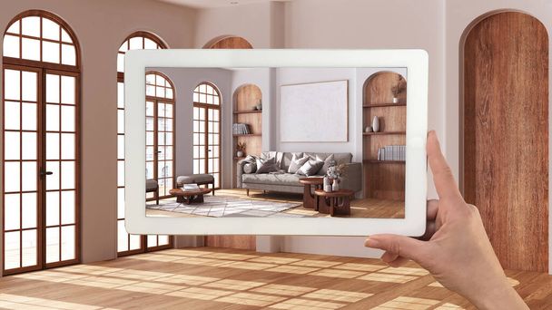 Augmented reality concept. Hand holding tablet with AR application used to simulate furniture and design products in empty interior with parquet floor, farmhouse living room - Photo, Image