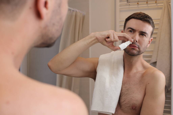 portré jóképű fiatalember spriccelés orra előtt tükör a fürdőszobában - Fotó, kép