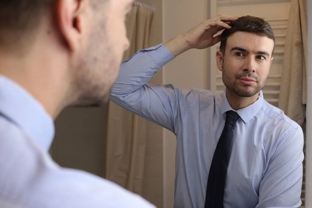 портрет красивого молодого человека в рубашке и галстуке перед зеркалом в ванной комнате - Фото, изображение