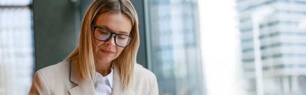 Businesswoman in glasses drinking coffee and making notes while working in cafe. High quality photo - Fotoğraf, Görsel