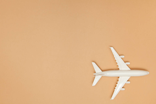 Airplane model. White plane on light brown background. Travel vacation concept. Summer background. Flat lay, top view, copy space. - Photo, image