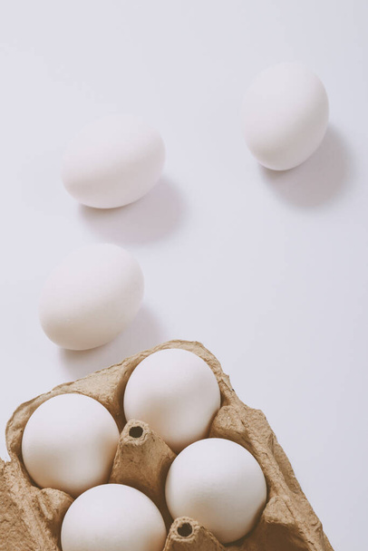 Uova bianche su sfondo brillante e in vassoio di uova marroni. Concentrazione selettiva. Scena concettuale. - Foto, immagini