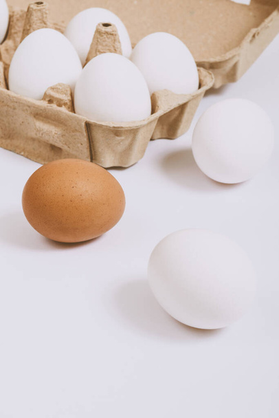 White and brown eggs on bright background and white eggs in brown egg tray. Selective focus. Concept scene. - Photo, Image