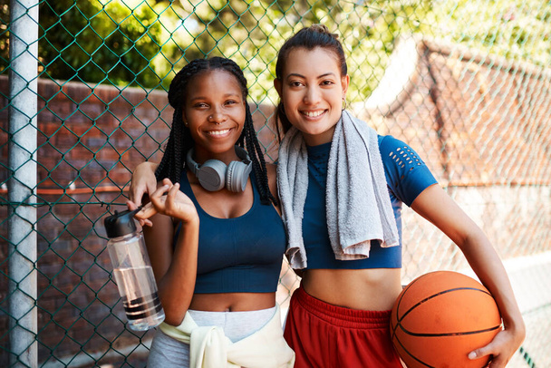 Eram melhores amigos e amantes de basquete. Retrato de duas mulheres jovens desportivas em pé contra uma cerca em uma quadra de esportes - Foto, Imagem