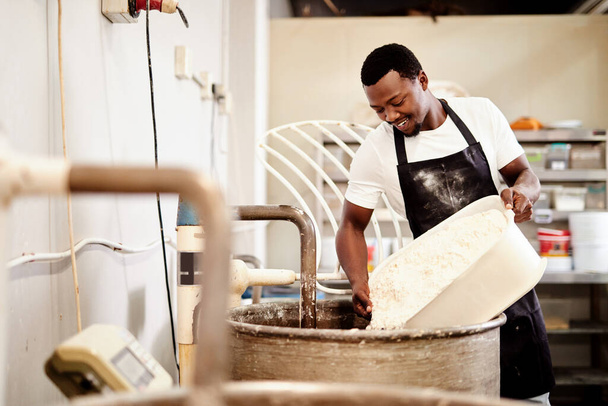 Vamos a empezar el proceso de amasado. un panadero vertiendo harina en una máquina de amasar - Foto, imagen