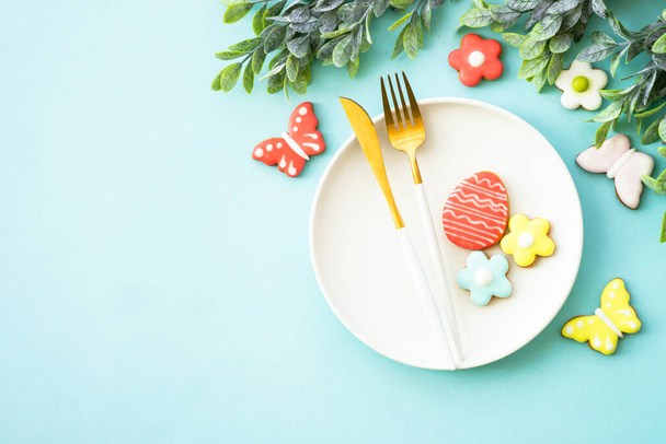 Wielkanocne jedzenie. Biały talerz z jajkami, wiosennymi kwiatami i ciasteczkami wielkanocnymi. Układy płaskie. - Zdjęcie, obraz