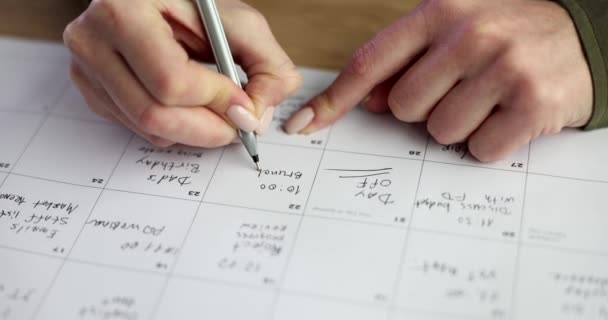 Vrouwenhanden schrijven een kalender met een pen, een close-up. Week planning, organisatie van taken - Video