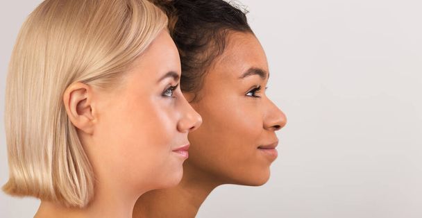 Two multiracial young women african american and blonde caucasian profile portrait with perfect fresh clean skin without makeup over white background, looking at copy space, banner, collage - Photo, Image