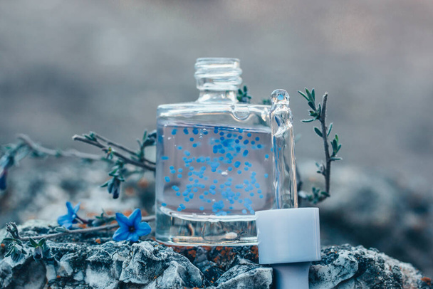 Cosmetic bottle with facial serum. Glass jar with a dropper. Blue cuticle oil with pellets has lavender scent. Beauty treatment concept. Anti aging products. Alternative medicine Copy space for text - Φωτογραφία, εικόνα