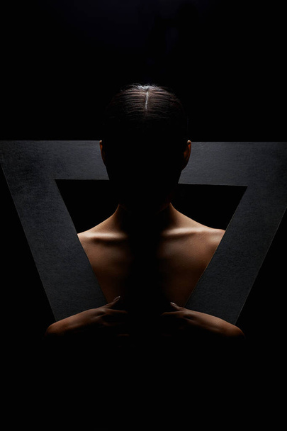 Üçgen içinde güzel çıplak bir kadın. Karanlıktaki çıplak kızın sanat portresi. siluet - Fotoğraf, Görsel