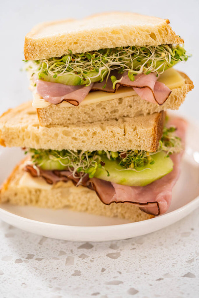 Stack of ham, cucumber, and sprout sandwiches on the white plate - Zdjęcie, obraz