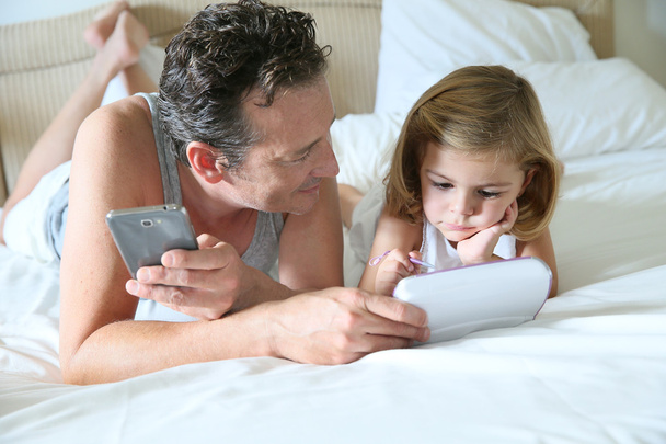 Man with smartphone and daughter with tablet - Foto, immagini