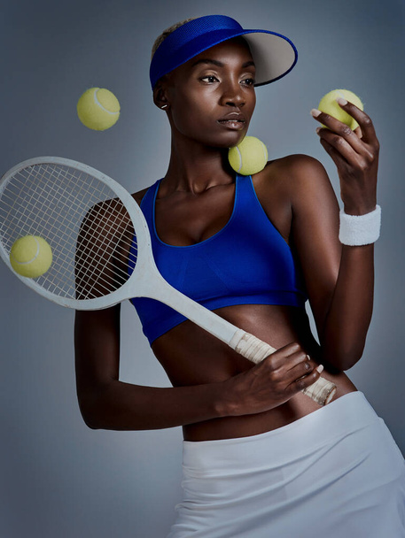 Nothing is impossible if your mindset it right. Studio shot of a sporty young woman posing with tennis equipment against a grey background - Foto, imagen
