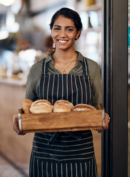 Je frischer, desto besser. eine junge Frau mit einer Auswahl frisch gebackener Brote in ihrer Bäckerei - Foto, Bild