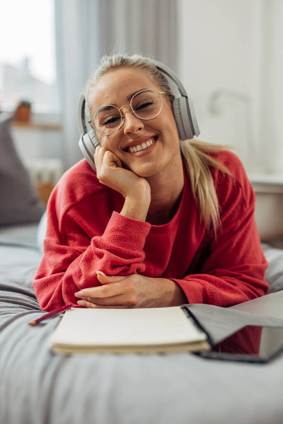 Portrait of a beautiful smiling Caucasian woman on a bed studying - Fotoğraf, Görsel