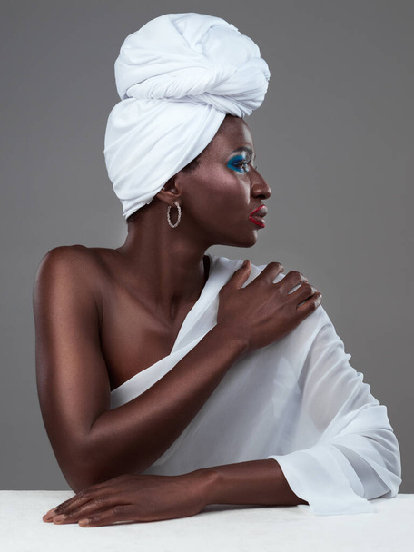 美しさのプロフィール。スタジオショットの魅力的な若い女性のポーズで伝統的なアフリカの衣装に対して灰色の背景 - 写真・画像