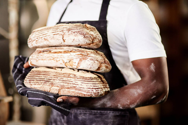 Da minha cozinha para a tua. um padeiro macho segurando pão recém-assado em sua padaria - Foto, Imagem