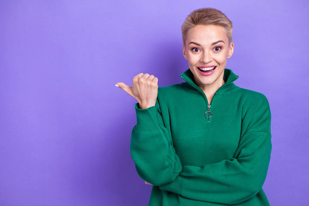 Photo portrait of overjoyed crazy funny reaction blonde short hair girl wear green jumper point thumb mockup news isolated on purple color background. - Φωτογραφία, εικόνα