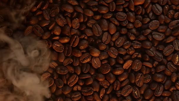 Tekstura palonej ziarna kawy jest podkreślona przez ciepłe żółte światło, lekki dym skrada się nad kawą. - Materiał filmowy, wideo