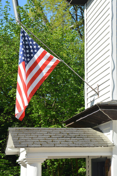 Americká vlajka jako vítr vlaje, americká vlajka proti zeleným stromům pozadí - Fotografie, Obrázek