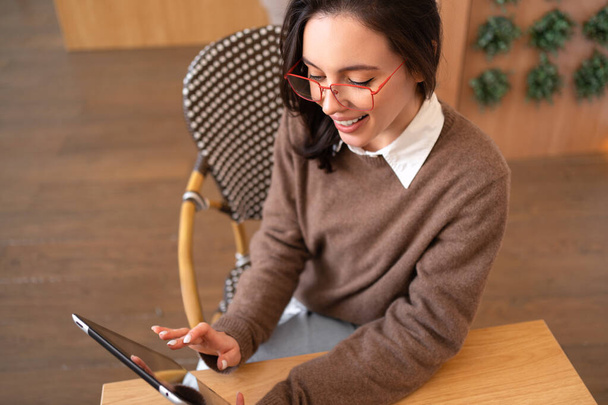 Femme utilisant un ordinateur tablette assis à son bureau vue grand angle. Technologies modernes et communication. Jeune femme étudiant ou travaillant en ligne sur le pavé tactile regardant l'appareil d'écran. - Photo, image