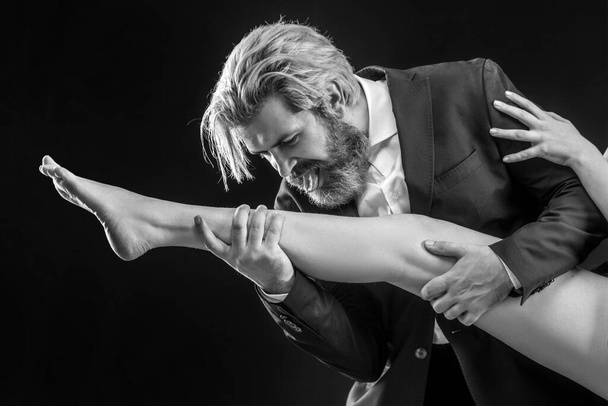 Strange bussinessman in suit licking female legs. Foot fetish. Luxury and patriarchy. Man lick leg - Foto, immagini