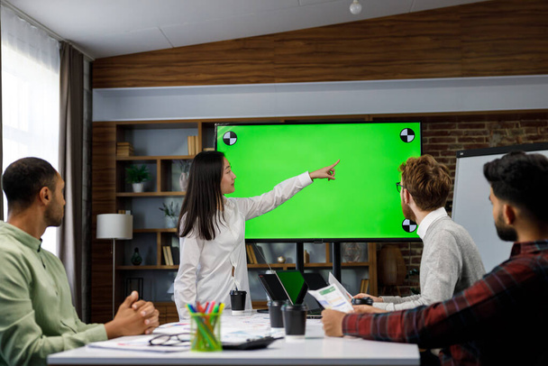 Marketing strategy analysis, stock market trading or corporate teamwork. A team of startups at a table with a large green screen TV. Mixed race business team - Photo, Image