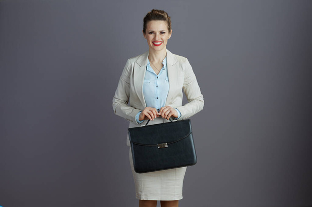 smiling stylish business woman in a light business suit with briefcase isolated on gray. - Photo, Image