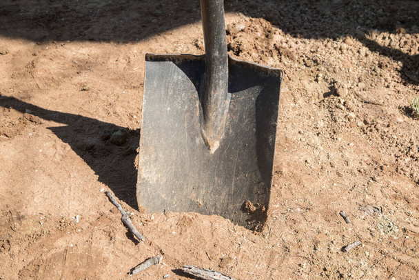 Shovel stuck in sandy soil closeup in sunny day - Photo, Image