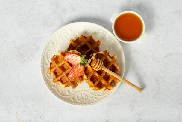 Belga liege waffles com morangos e mel em uma mesa leve. Vista lateral. - Foto, Imagem