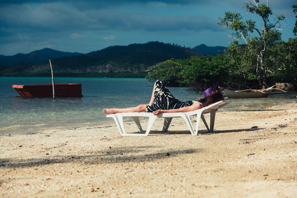 Mulher relaxante no leito solar nos trópicos
 - Foto, Imagem