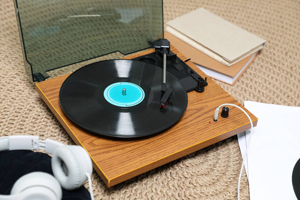 Stylish turntable with vinyl disc and headphones on carpet at home - Fotó, kép