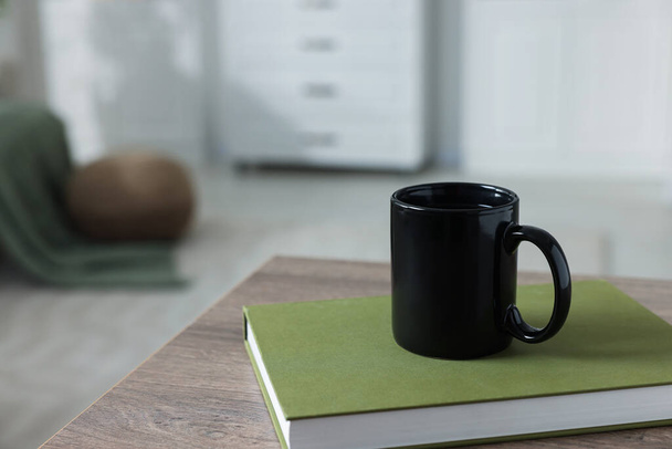 Ceramic mug of tea and book on wooden table. Mockup for design - Foto, imagen