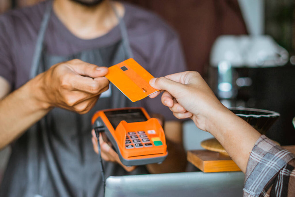 the hand of the male barista receiving the credit card from the customer - Fotó, kép