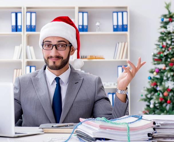 Ο νεαρός επιχειρηματίας γιορτάζει τα Χριστούγεννα στο γραφείο - Φωτογραφία, εικόνα