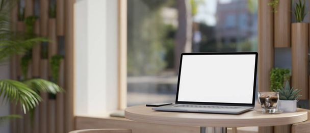 Közelkép a hordozható laptop fehér képernyős mockup, kávé csésze és dekoráció növény minimális fa asztal gyönyörű modern kávézó vagy együttműködő hely. 3D render, 3D illusztráció - Fotó, kép