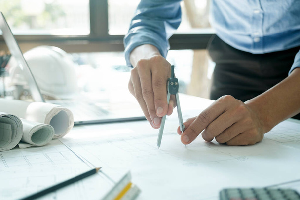 Close-up hands shot of engineer, developer, or architect standing working alone, drawing design of construction project with compass and equipments on desk. Engineer concept. - Foto, Imagem