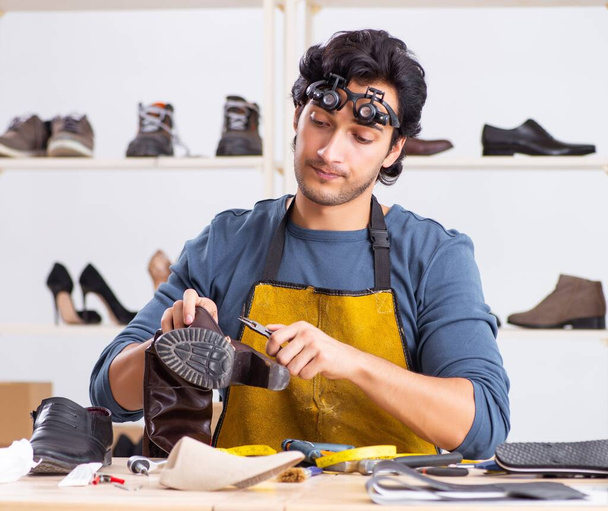 Le jeune homme réparant des chaussures en atelier - Photo, image