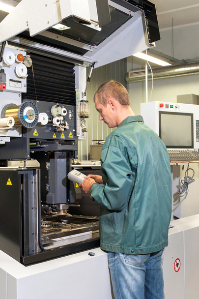 Ouvrier opérant une machine CNC industrielle dans l'atelier
. - Photo, image