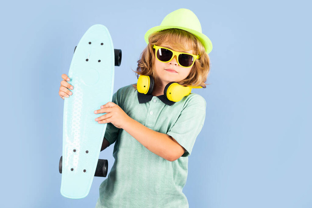 Niño con monopatín. Tablero de patinaje infantil. Deporte saludable y actividad para escolares en verano. Diversión deportiva - Foto, imagen