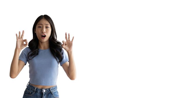 Young asian woman over white background doing ok sign with hands, OK symbol, Welcome, Agree, Join, Do as instructed, Follow orders, Acceptance of all conditions. - Photo, Image
