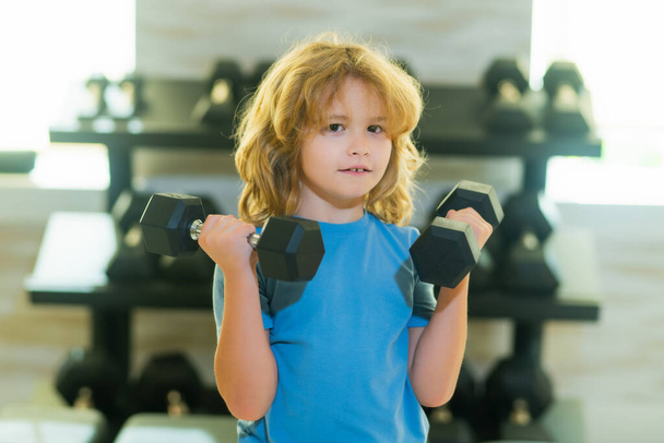 Kid raising a dumbbell. Cute child training with dumbbells. Kids fitness. Kid boy exercising with dumbbells. Healthy kids - Foto, Imagen