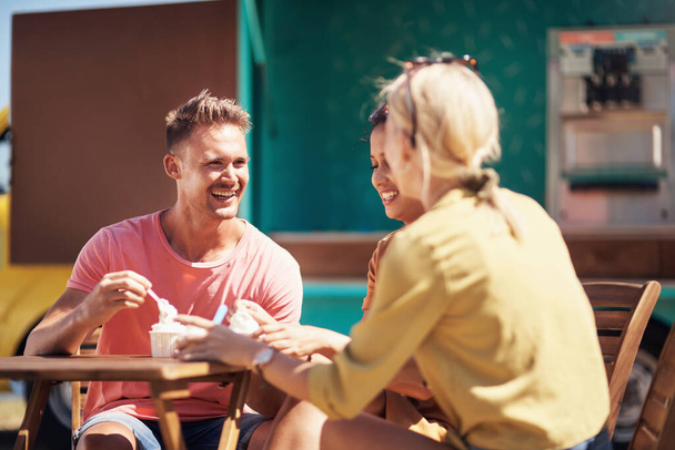 Πώς είναι το παγωτό; μια ομάδα από χαρούμενους νεαρούς φίλους που γευματίζουν μαζί έξω δίπλα σε έναν παραλιακό περίπατο - Φωτογραφία, εικόνα